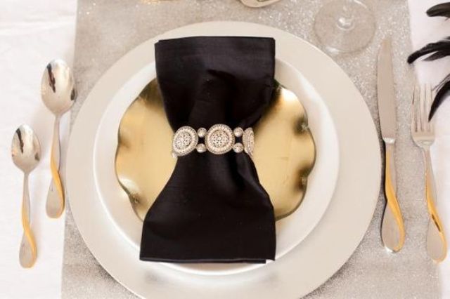 a gold plate, a silver glitter place mat and a black napkin with an embellished ring