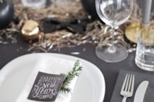 08 a black tablescape with black and metallic ornaments and table runner, chalkboard cards and white chargers