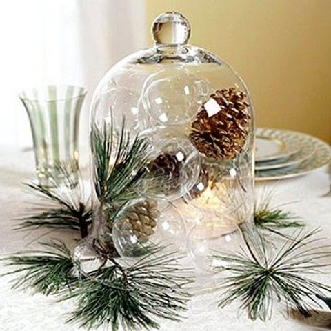 a cloche with sheer glass ornaments and pinecones plus pine needles as a centerpiece