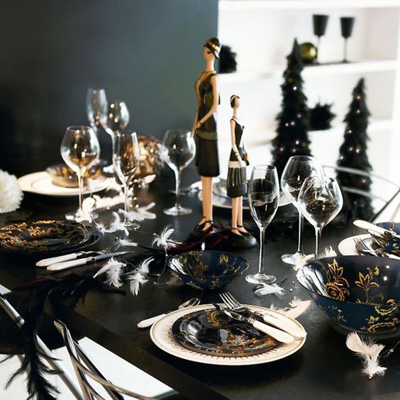 a black table with refined navy and gold tableware, feathers and glam figurines for a girls' branch