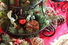 09 a cupcake stand with evergreens, pinecones and red ornaments for a traditional touch
