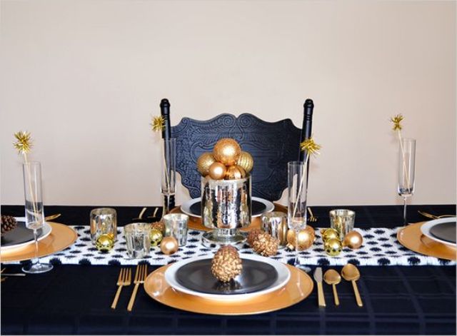 a gold charger, cutlery and ornaments blended with black and white plates and table runners