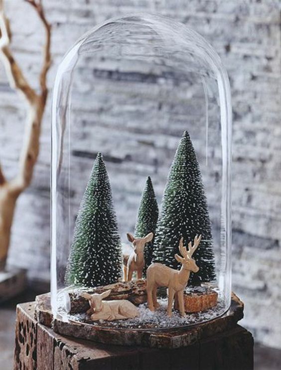 a cloche with pipe cleaner trees, wood and deer figurines for a cozy look