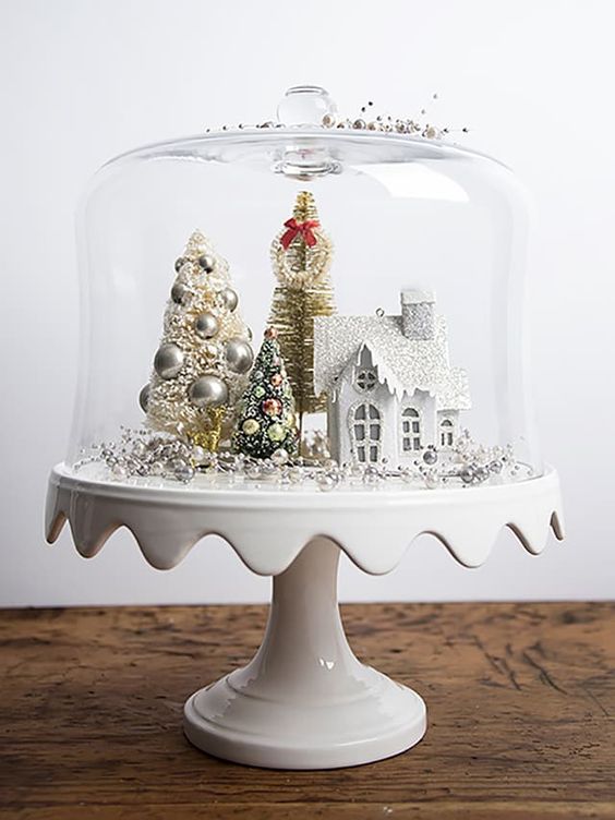 a cloche with a bead and ornament tree, tinsel trees and a white house for a vintage look