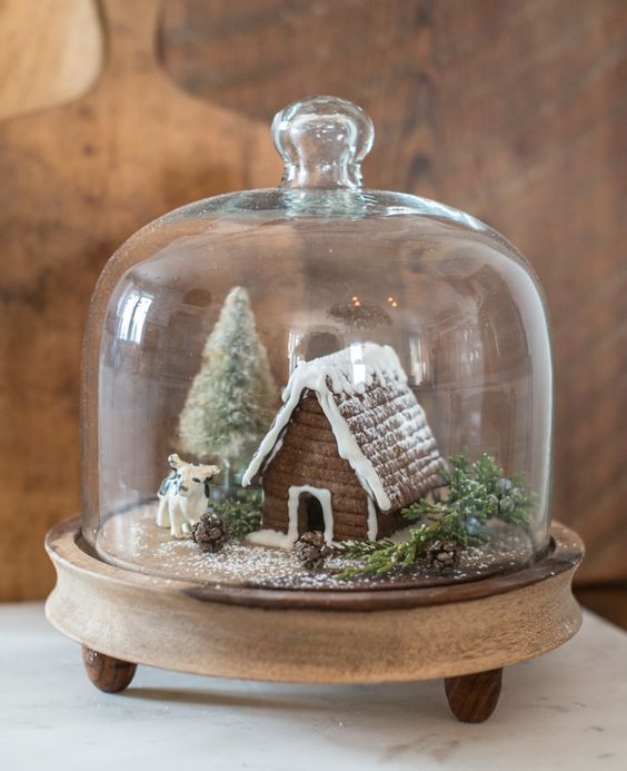 a cloche with a gingerbread house, a tinsel tree and little figurines will be a cool winter decoration