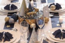 15 a navy and white tablescape with metallic ornaments, trees and figurines and some stars