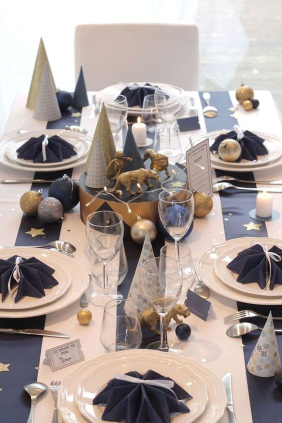 a navy and white tablescape with metallic ornaments, trees and figurines and some stars