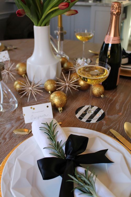 an elegant black and white table setting with black bows, metallic ornaments and rosemary
