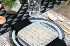 24 a printed placemat, a black and white charger and a table runner, geometric vases and gold touches
