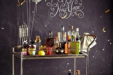 a NYE bar cart decorated with balloons and with a whole assortment of drinks and appetizers is a must for a NYE party