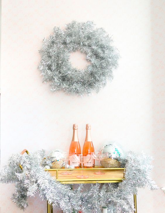 a NYE bar cart decorated with silver tinsel and disco balls plus a silver tinsel wreath over the bar cart