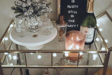 a NYE bar cart with lights, a flocked Christmas tree, a deer, a sign and some candleholders is lovely