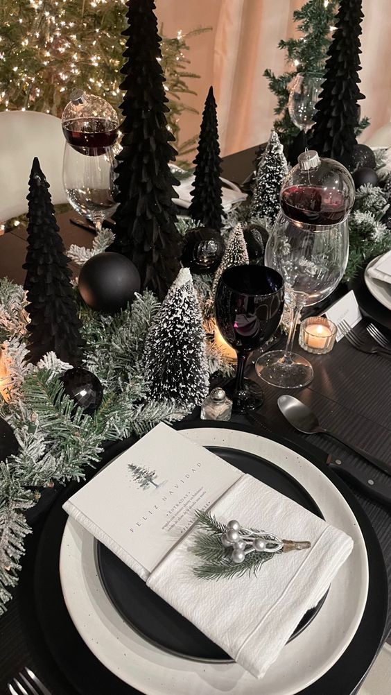 a NYE table setting with snowy bottlebrush trees and black ones, black and white plates and candles