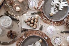 a New Year tablescape with woven placemats, grey plates, a tray with candles, lights and evergreens