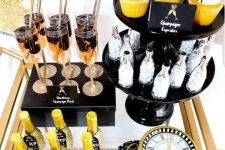 a brass bar cart with glitter bottles, fringe cupcake toppers and a glitter clock is a gorgeous idea for a NYE party