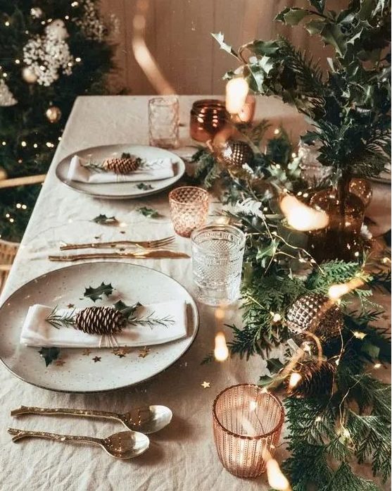a bright holiday tablescape with an evergreen runner, lights, metallic ornaments, star print plates and copper candleholders