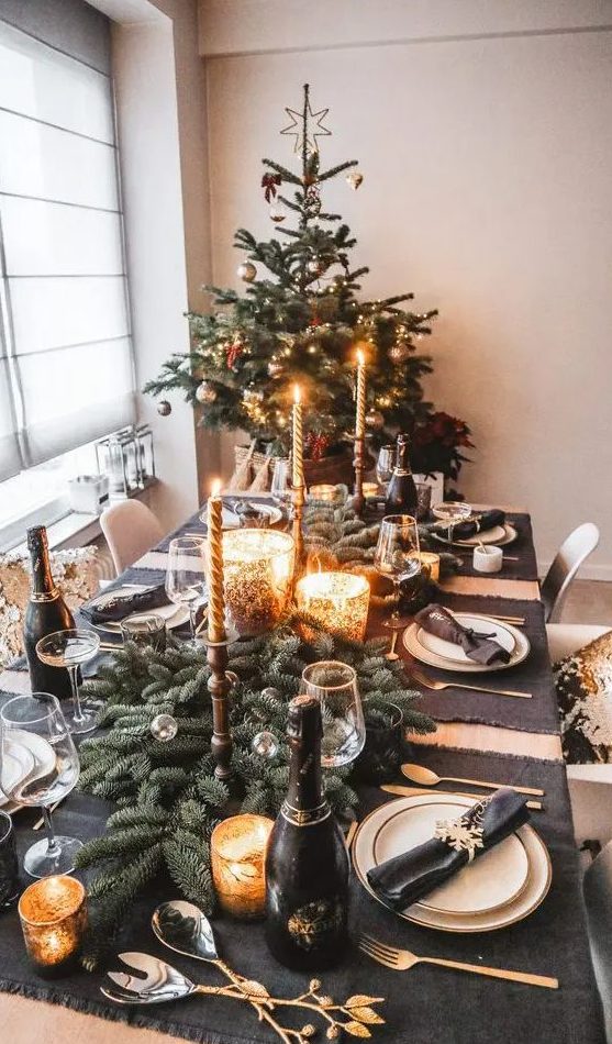 a fabulous holiday tablescape with graphite grey placemats, an evergreen runner, mercury glass candleholders, chic gold cutlery
