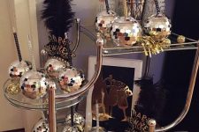 a funny NYE bar cart with disco ball glasses for drinks and some alcohol is a super fun and catchy idea