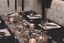 a glam black, silver and gold tablescape with a sequin table runner, black candles in gold candleholders, white plates
