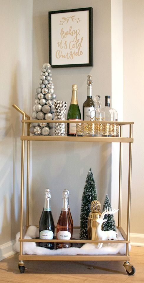 a holiday bar cart with a silver and disco ball Christmas tree, bottlebrush trees, a deer and some alcohol