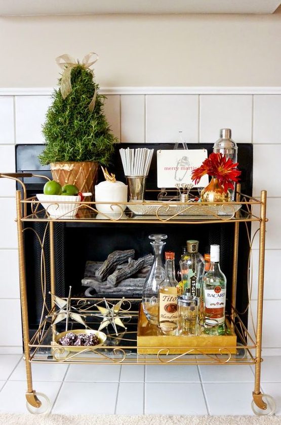 a holiday bar cart with an evergreen tree in a pot and some gilded star ornaments for any holiday party