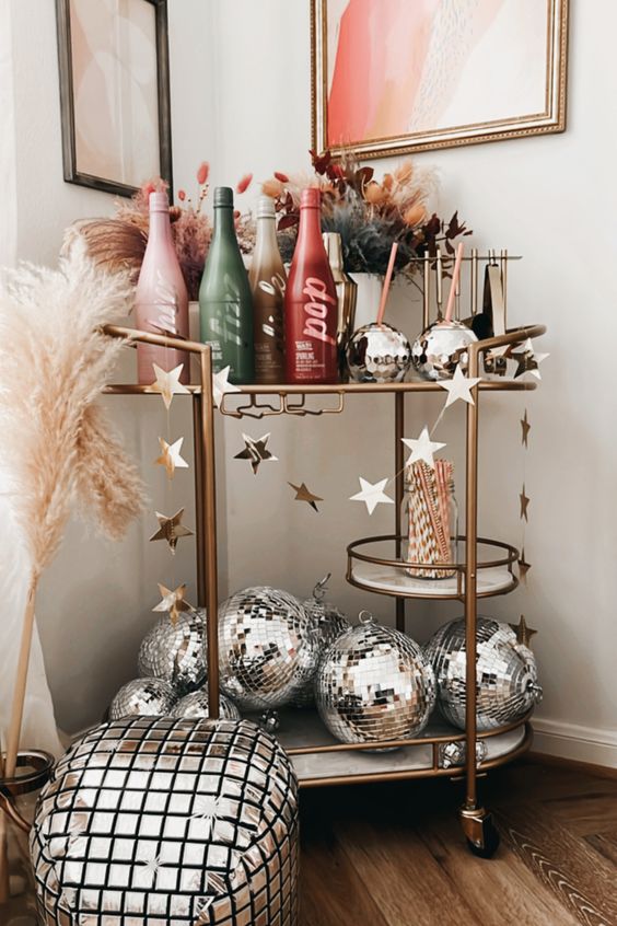 a holiday bar cart with silver disco balls, colorful bottles, dried blooms and grasses is an amazing idea for NYE