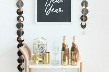 a pretty NYE bar cart with gold barware, a star, some popcorn, gold glasses and some alcohol is simple