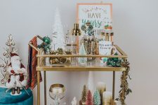 a pretty holiday bar cart with bottlebrush and other trees, candles, garlands and some pretty barware