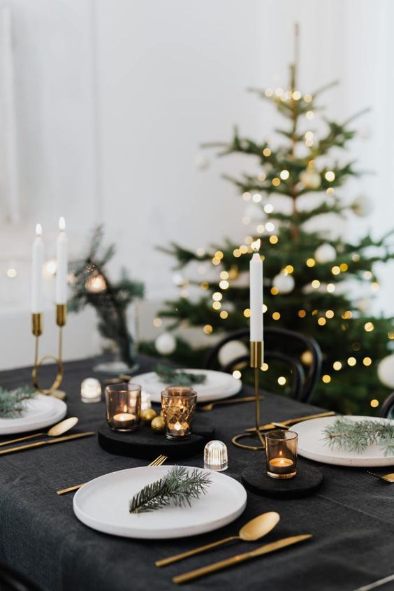 a simple NYE tablescape with black linens, candles, evergreens and gold cutlery and candleholders can be set up in minutes