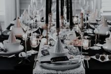 an awesome black and white NYE tablescape with a silver sequin runner, black candles, white porcelain and silver napkins