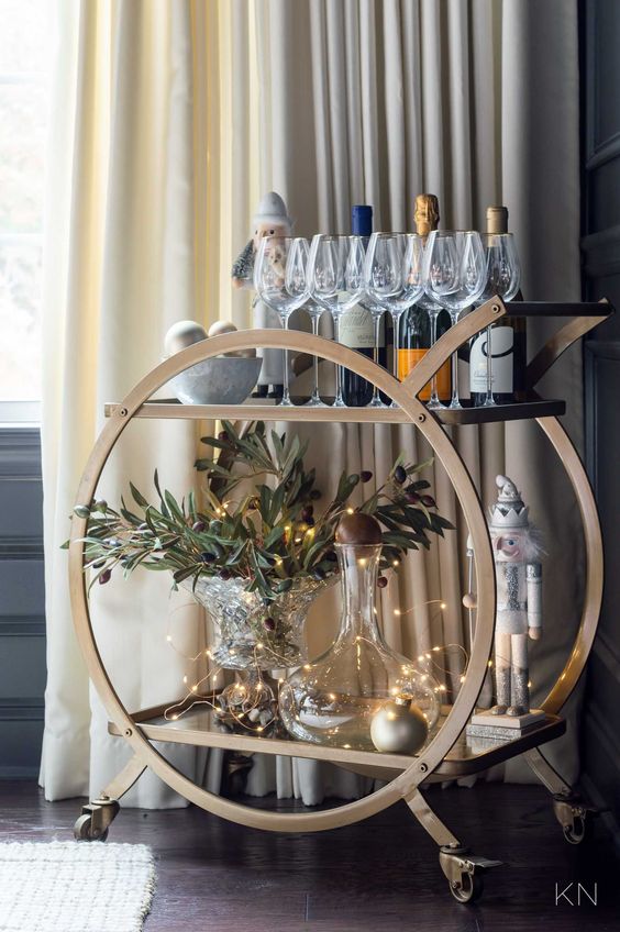 an elegant NYE bar cart with lights, greenery, metallic ornaments and figurines is a good idea for the holidays