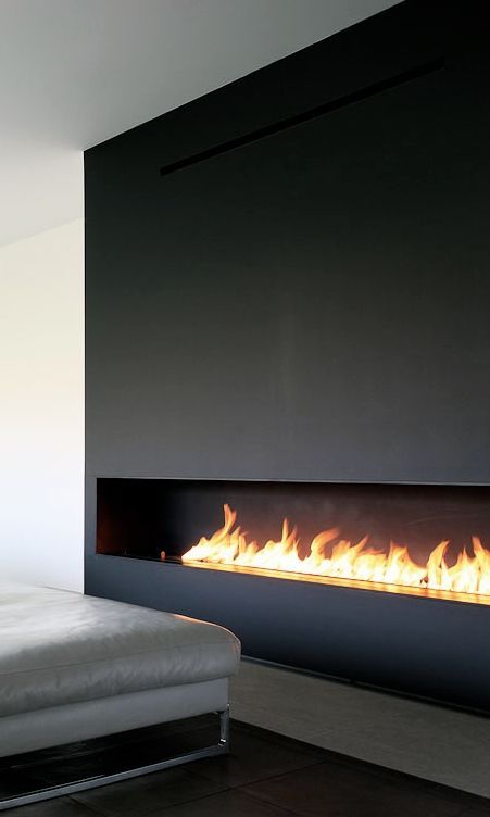 a long horizontal ethanol fireplace fully clad with black metal takes the whole wall and become a focal point here