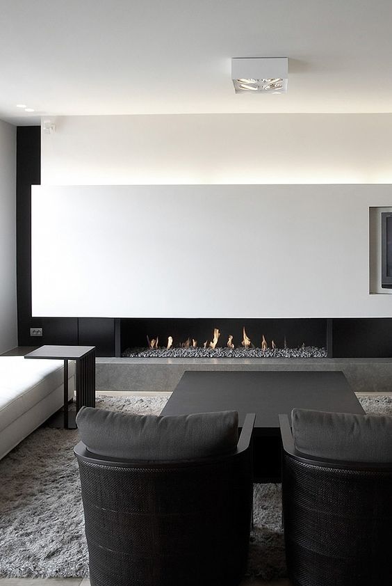 a minimalist monochromatic space enjoys a gorgeous fireplace that warms it up