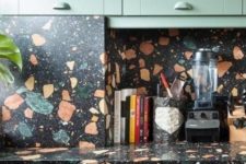 12 light green cabinets with dark terrazzo countertops and a backsplash that match