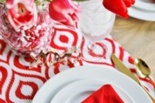 15 red envelope-shaped napkins, a red and white table runner, a bold centerpiece with blooms and candies in the vase