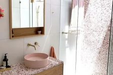 a chic contemporary bathroom with a pink terrazzo wall in the shower, a floating vanity with a pink terrazzo countertop plus a pink sink