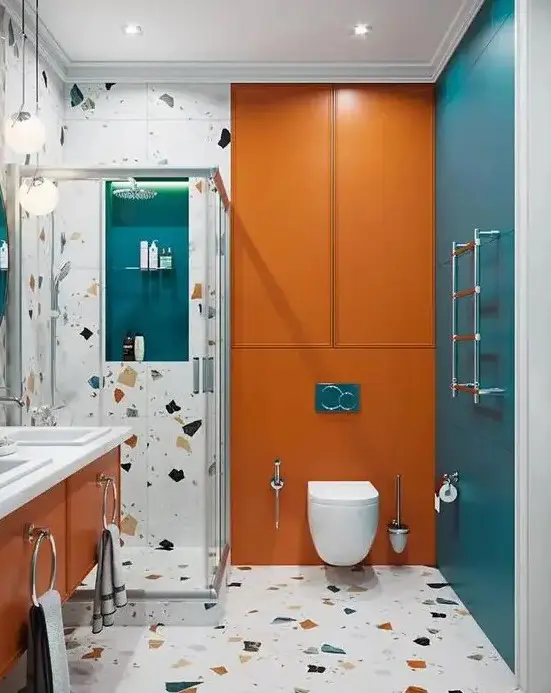 a colorful bathroom with blue and orange touches, terrazzo and white appliances and built-in lights