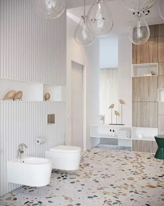 a creative bathroom with white walls and a bright terrazzo floor, white appliances and a plywood storage unit plus pendant lamps