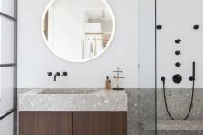 a minimalist bathroom in neutrals is made eye-catchy with grey terrazzo on the floor and countertops and black fixtures