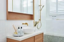 a pretty modern bathroom clad with white tiles and green terrazzo, a stained vanity, a mirror cabinet, gold fixtures is amazing