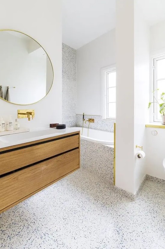 A refined light filled bathroom with white walls and a white and blue terrazzo floor that covers one wall and the tub, too