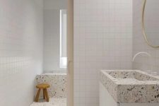 an all-neutral bathroom clad with white square tiles, and done with white terrazzo flooring and appliances is amazing