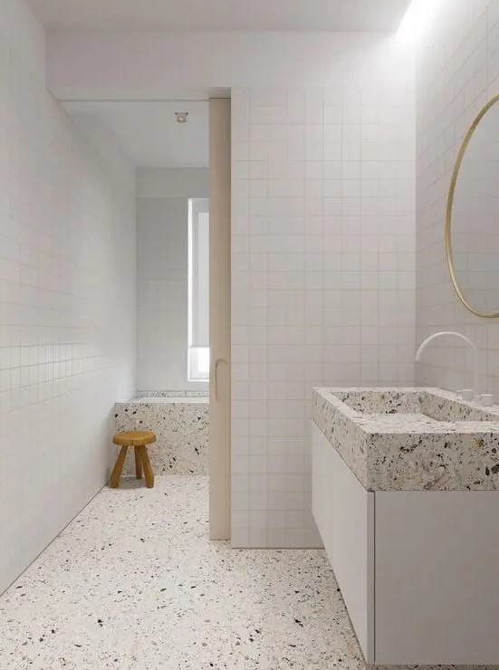 an all-neutral bathroom clad with white square tiles, and done with white terrazzo flooring and appliances is amazing