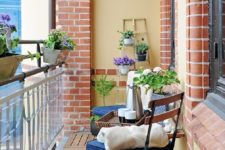 02 a small balcony with a couple of folding chairs with cushiones, a foldable table and plants with bright flowers