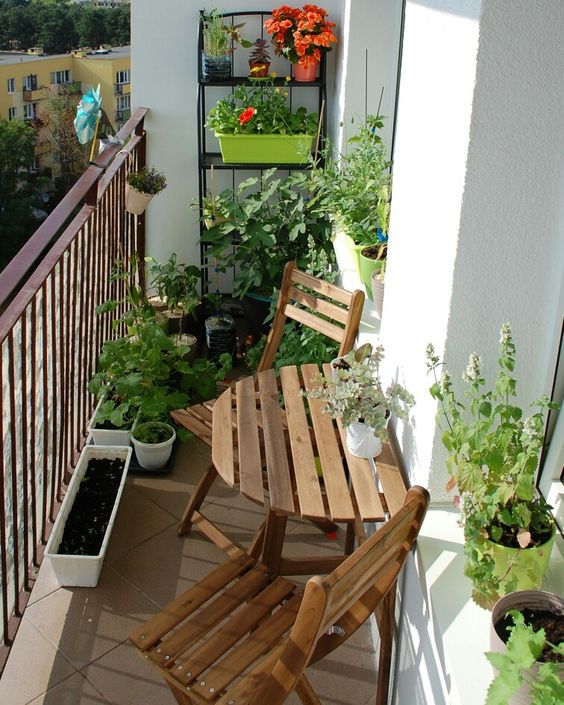 a little spring balcony with stained folding furniture, potted greenery and flowers is a lovely space to have a cup of tea
