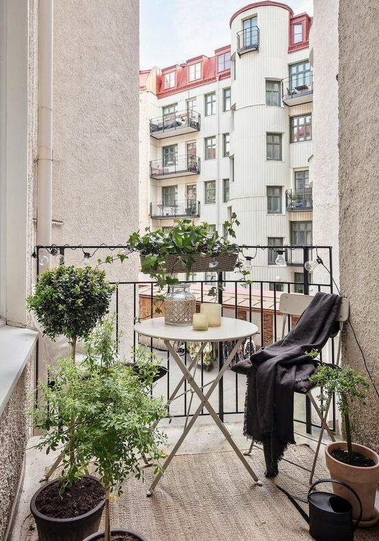 a tiny balcony styled for spring, with folding furniture and lots of potted greenery to refresh the space