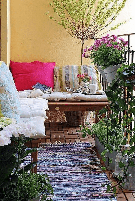 colorful pillows and a boho rug, potted greenery and flowers are bold and cool for a boho balcony