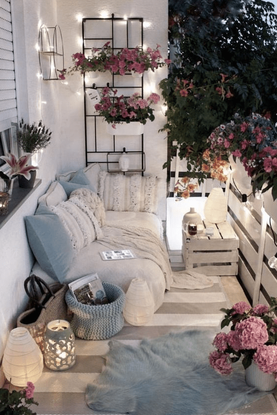 light blue pillows and a basket, potted pink flowers and some lights and lanterns will make your balcony tender and spring-like