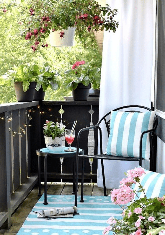 light blue printed pillows and a rug and potted pink flowers turn this balcony in a light inviting space