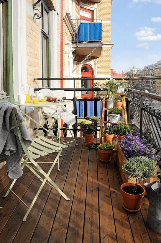 lots of greenery and bright blooms in wooden and terra cotta pots will make your balcony feel like spring and a bit rustic